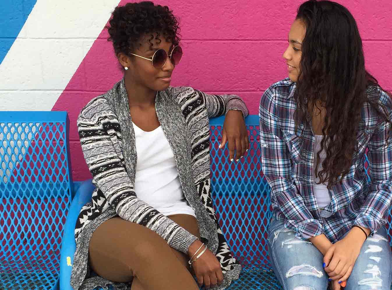 Deux jeunes femmes assises sur un banc bleu